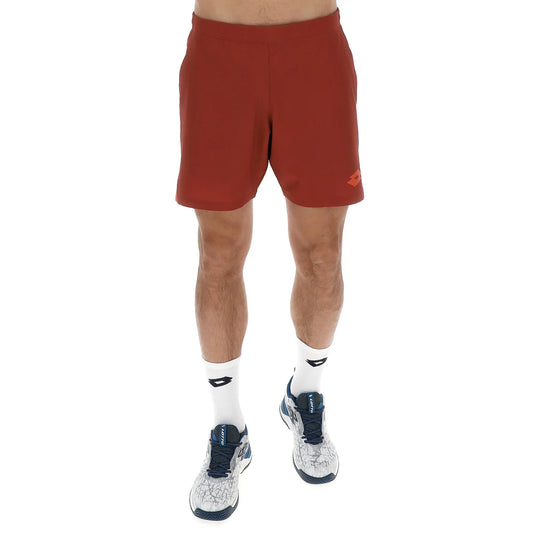 מכנסי גברים לוטו PANTALONI CORTI TENNIS TECH D1 ROSSO SCURO LOTTO בצבע אדום כהה על גבר בטרנינג עם נעלי ספורט.