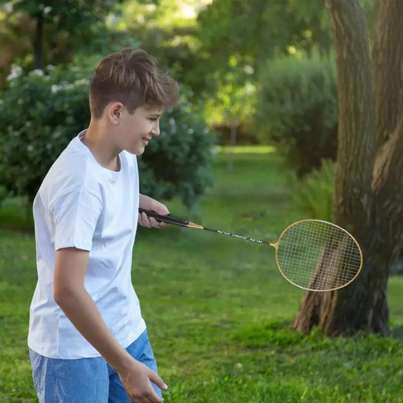 ילד משחק עם מחבטי בדמינטון מקצועיים | ציוד בדמינטון בפארק ירוק