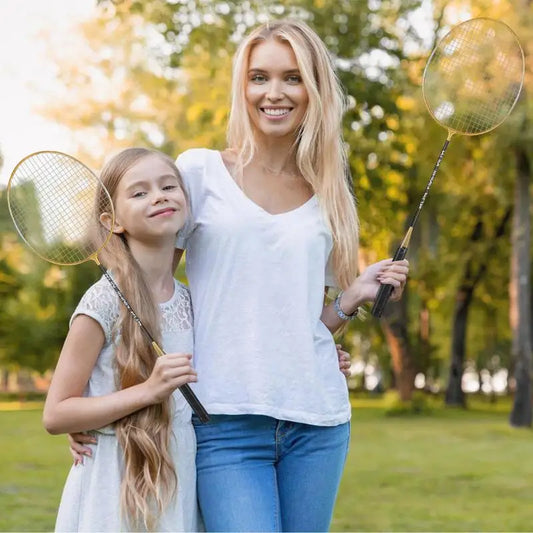 אמא וא daughter holding מחבטי בדמינטון מקצועיים | ציוד בדמינטון בפארק, נהנות מפעילות ספורטיבית.